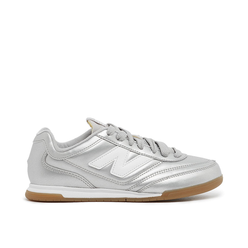 New Balance Wmns URC42CA sneaker with silver metallic leather upper, contrasting N logo, EVA cushioning, and breathable mesh lining for comfort and style.