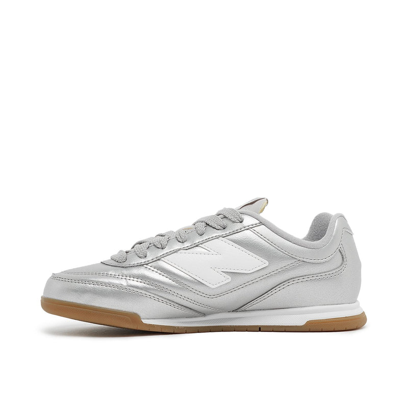 New Balance Wmns URC42CA sneaker with silver metallic leather upper, contrasting N logo, EVA cushioning, and breathable mesh lining for comfort and style.