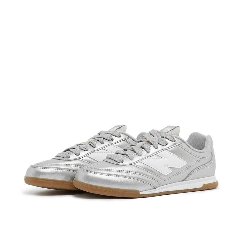 New Balance Wmns URC42CA sneaker with silver metallic leather upper, contrasting N logo, EVA cushioning, and breathable mesh lining for comfort and style.