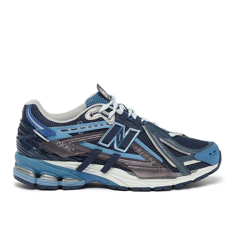 New Balance U1906AA sneaker with grey mesh upper, beige and brown overlays, NLock Lacing system, and cushioned sole with N-Ergy and ABZORB SBS pods.
