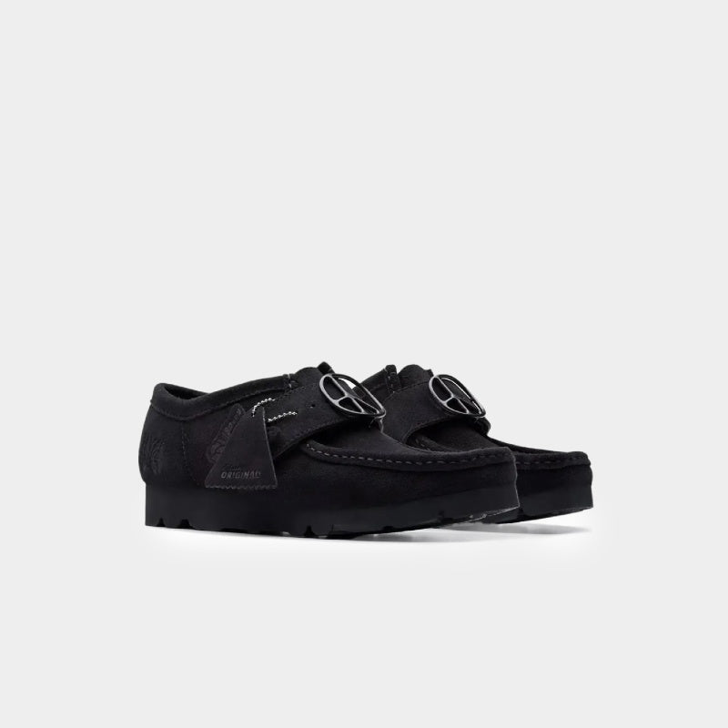 Clarks x Needles Wallabee boot featuring suede upper, debossed butterfly detail, and metal peace sign buckle on adjustable strap.