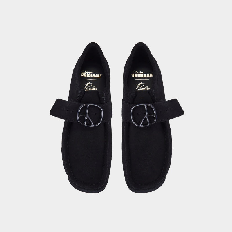 Clarks x Needles Wallabee boot featuring suede upper, debossed butterfly detail, and metal peace sign buckle on adjustable strap.