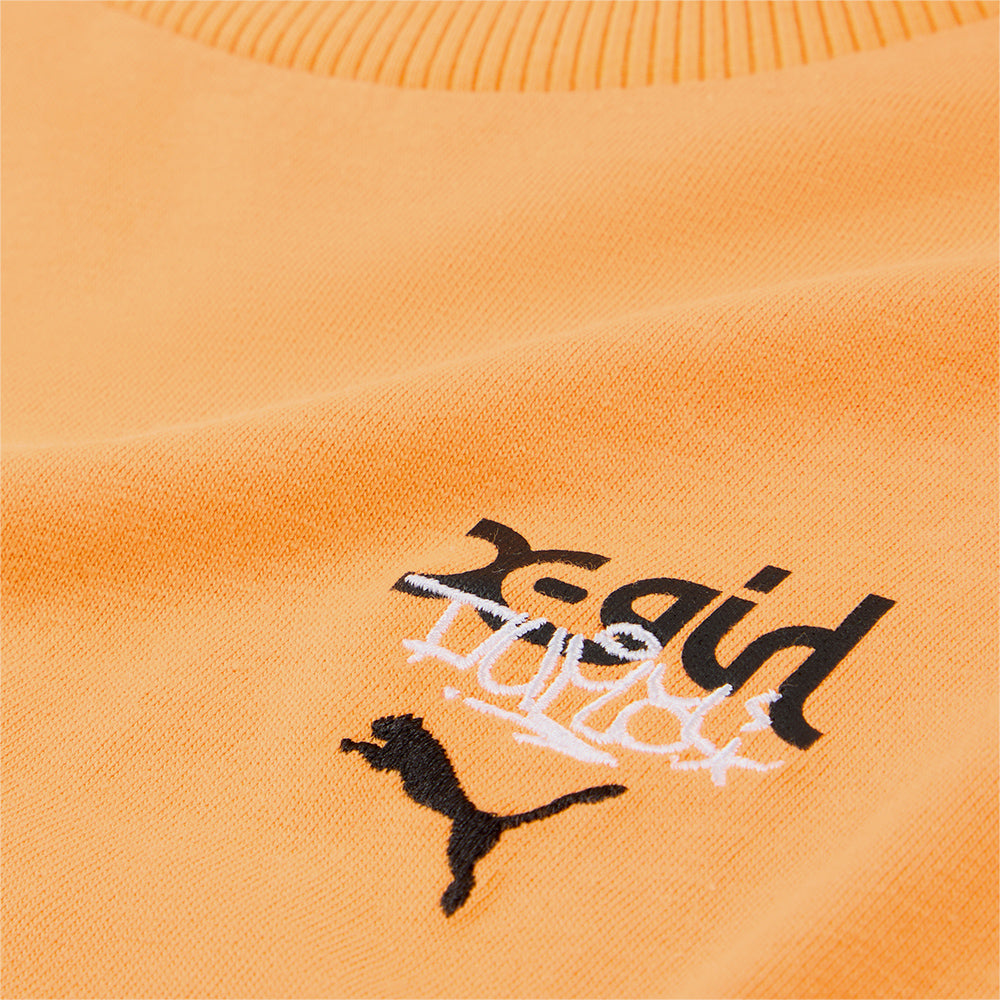 PUMA x X-GIRL tee featuring bold rubber print graphic on the front and contrast stitching, showcasing a modern streetwear style with a graffiti-inspired, DIY vibe.