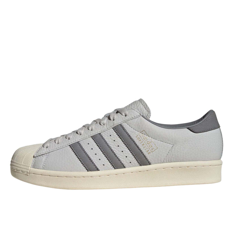 Grey adidas Superstar shoes with tonal shades and gold foil branding, inspired by the original 1969 design
