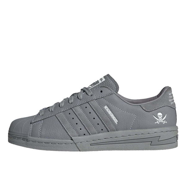 adidas Superstar x NEIGHBORHOOD sneakers with matte black leather, white stitching, and debossed logo and skull graphic.