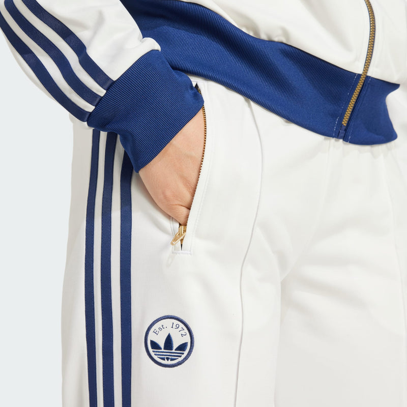 Adidas Firebird track pants featuring classic 3-Stripes, signature tricot sheen, and colors inspired by international competition, embodying a timeless sports style.



