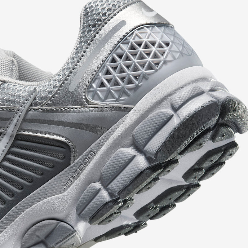 Nike Zoom Vomero with Wolf Grey, White, Metallic Silver, Cool Grey, and Metallic Platinum tones, featuring a breathable mesh upper, leather overlays, plastic lace cage, honeycomb heel counter, and 3M reflective accents.