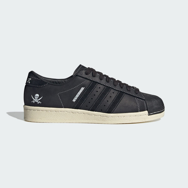 Adidas Superstar x NEIGHBORHOOD 30th Anniversary edition sneakers with matte black leather, white stitching, and iconic skull graphic.