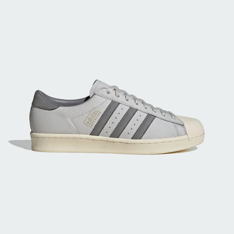 Grey adidas Superstar shoes with tonal shades and gold foil branding, inspired by the original 1969 design