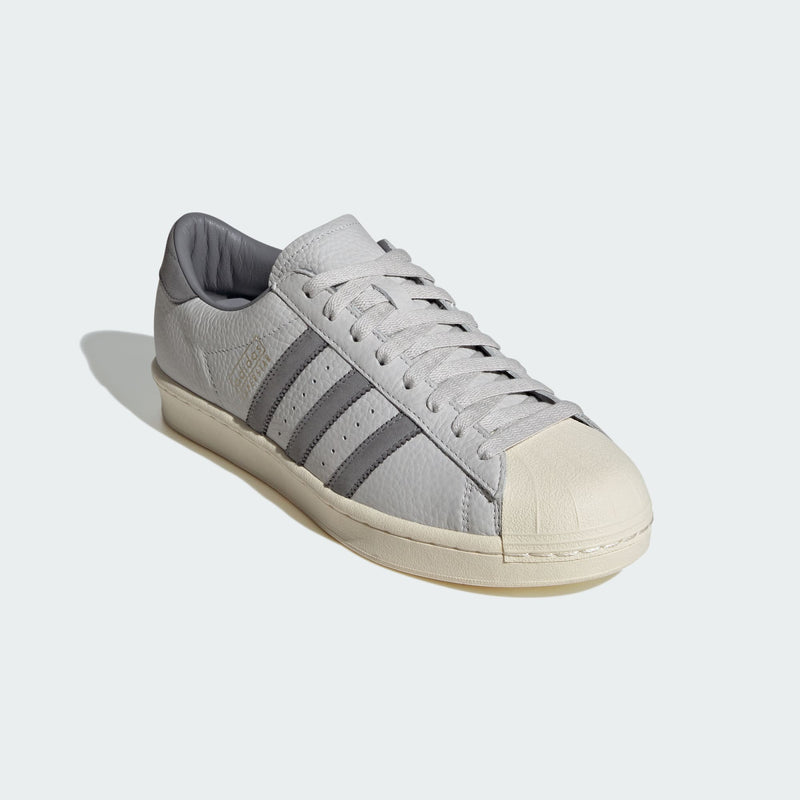 Grey adidas Superstar shoes with tonal shades and gold foil branding, inspired by the original 1969 design