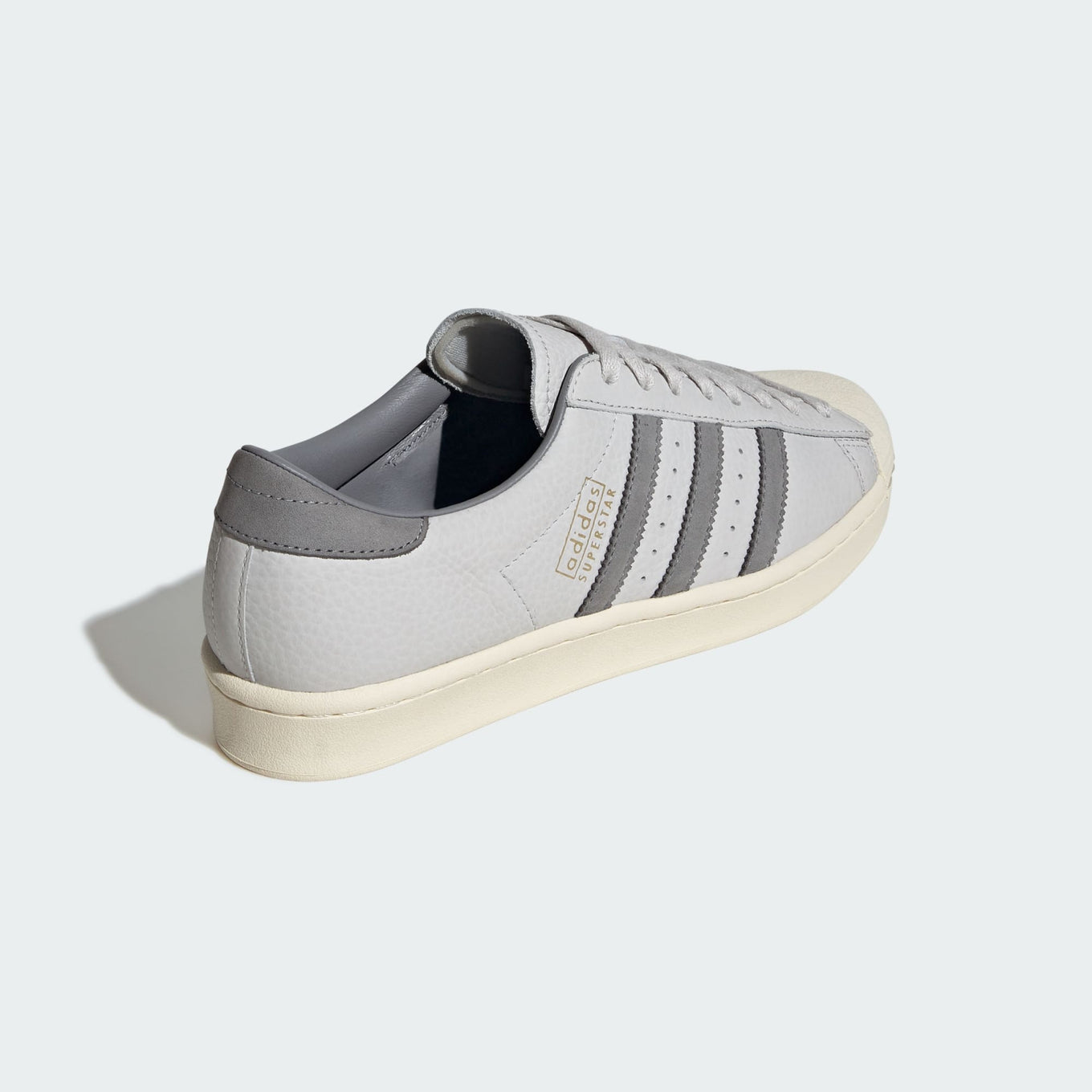 Grey adidas Superstar shoes with tonal shades and gold foil branding, inspired by the original 1969 design