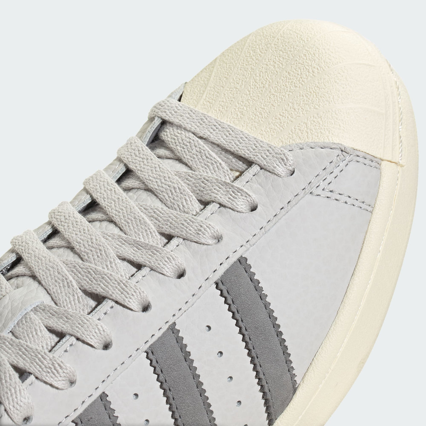 Grey adidas Superstar shoes with tonal shades and gold foil branding, inspired by the original 1969 design