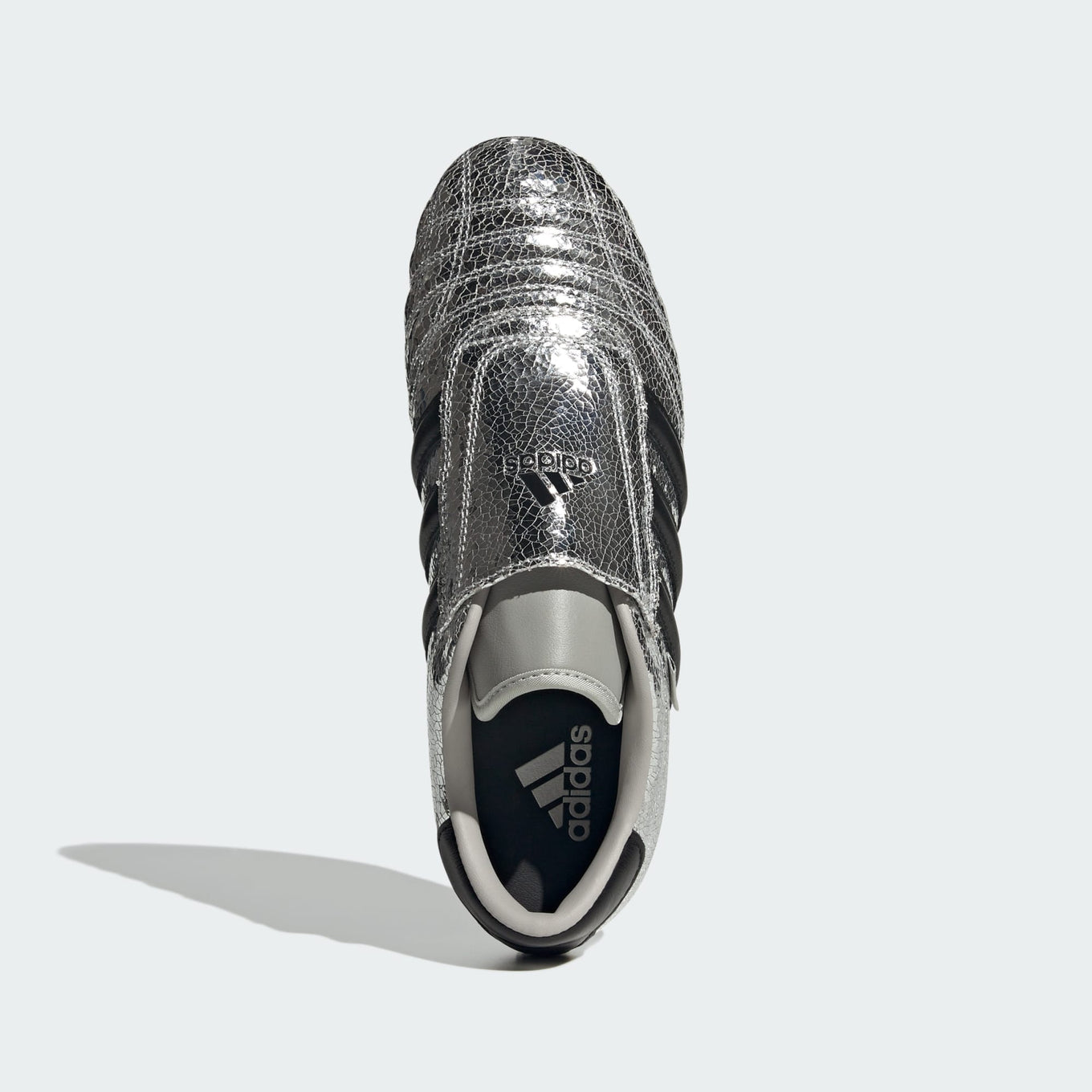 adidas Taekwondo trainers with a cracked metallic leather upper, slip-on design, and low-profile rubber outsole for a sleek, streetwear-inspired look.
