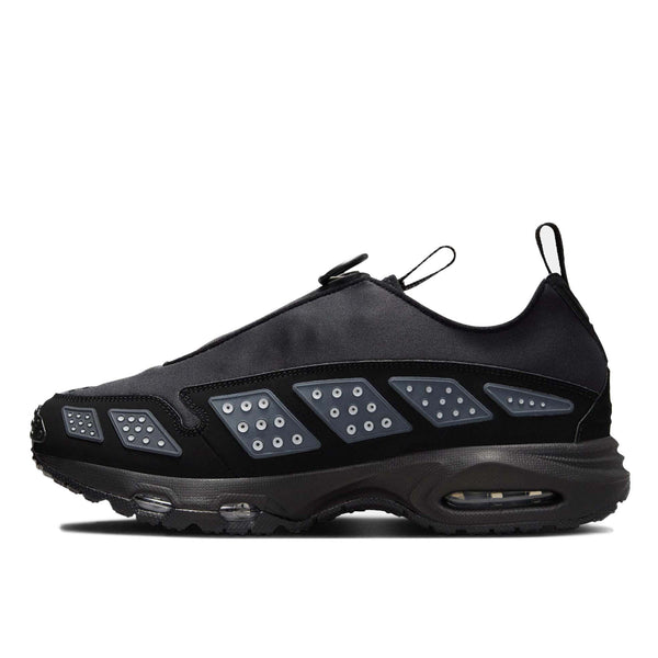 Air Max SNDR sneaker with a bold design featuring Silver accents, a black zip-up shroud, reflective design panels, Max Air cushioning in the heel, and Nike Air in the forefoot. Unzipped shroud reveals ""6453"" representing Nike’s global office numbers.