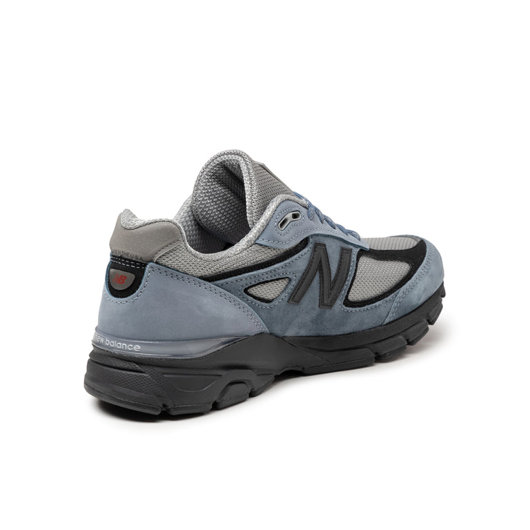 The revival of the New Balance 990 v4 after 8 years, featuring gray mesh with blue suede overlays and black details. Made in the USA with EnCap cushioning for comfort.