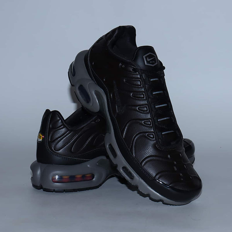 Air Max Plus sneaker in Black Tea synthetic leather with rippling design, Petra Brown-painted midsole, Max Air units, glossy finishes, and plated Swoosh logos