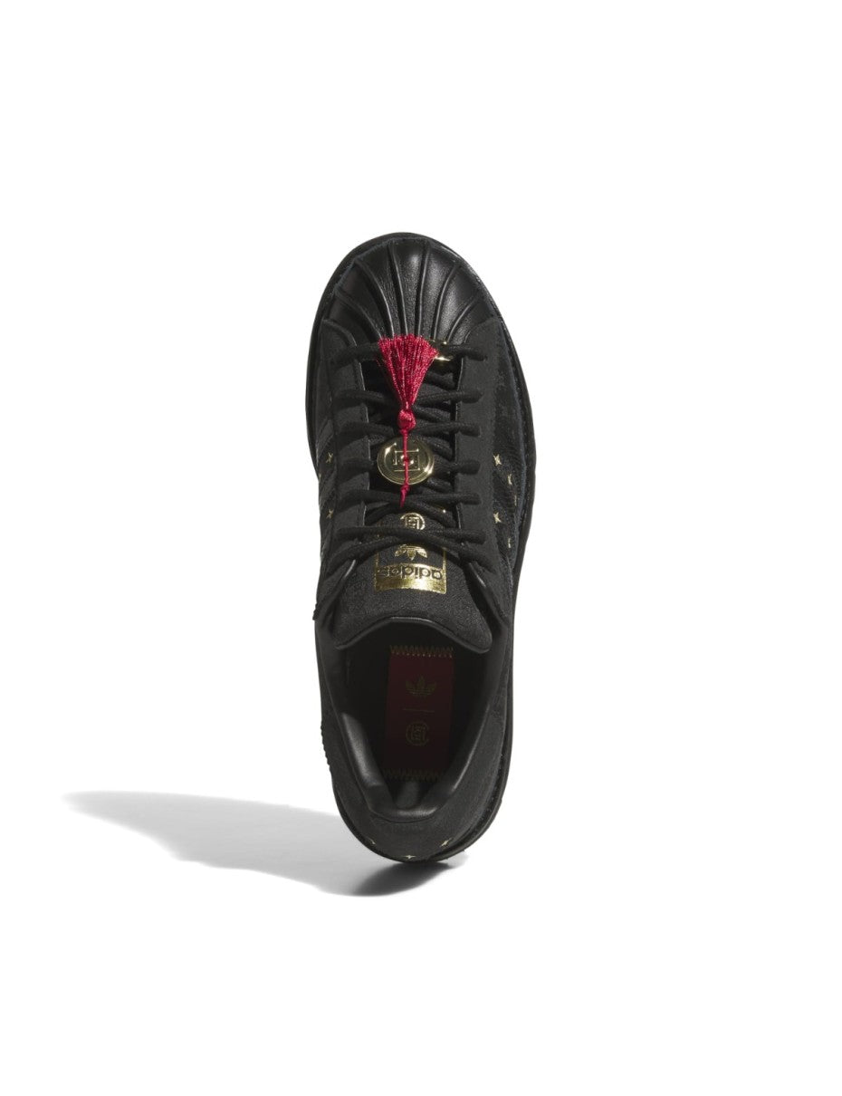 adidas Superstar x CLOT sneaker with snakeskin-patterned 3-Stripes, monogram print, gold details, red string accents, and a rippled outsole for a bold Lunar New Year tribute.