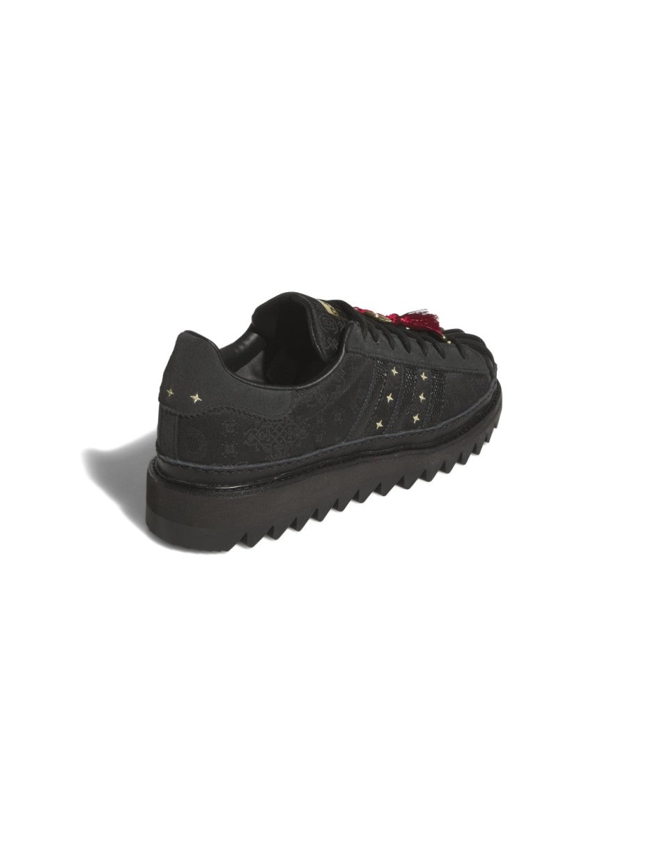 adidas Superstar x CLOT sneaker with snakeskin-patterned 3-Stripes, monogram print, gold details, red string accents, and a rippled outsole for a bold Lunar New Year tribute.