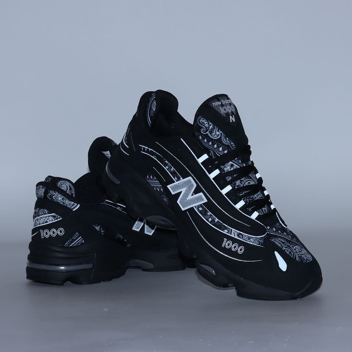 atmos x New Balance M1000 sneakers in black nubuck with bandana pattern details and monochrome color scheme