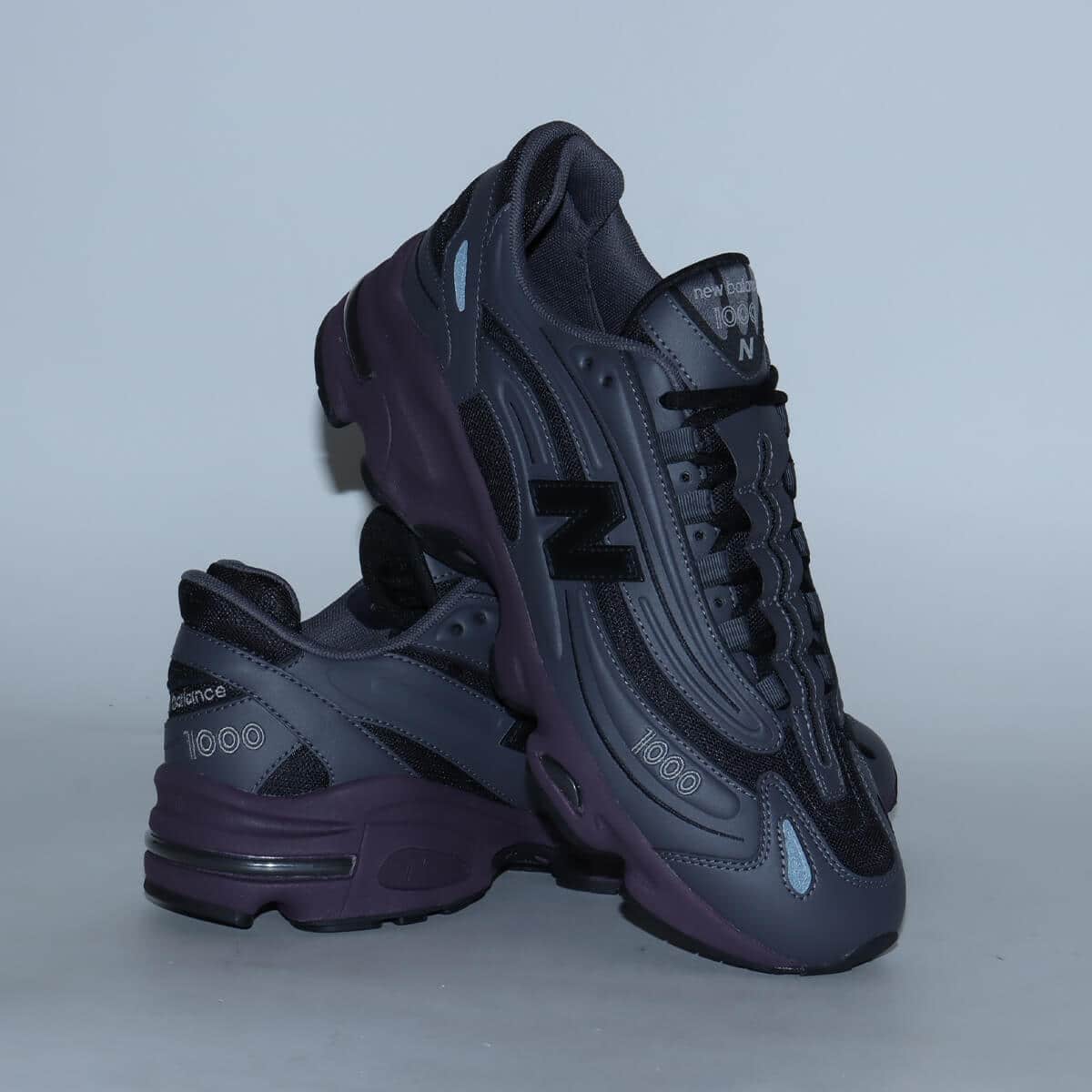 New Balance "Grey Day" inspired grey and black sneaker with plum midsole, leather and mesh construction, and signature "N" logo.