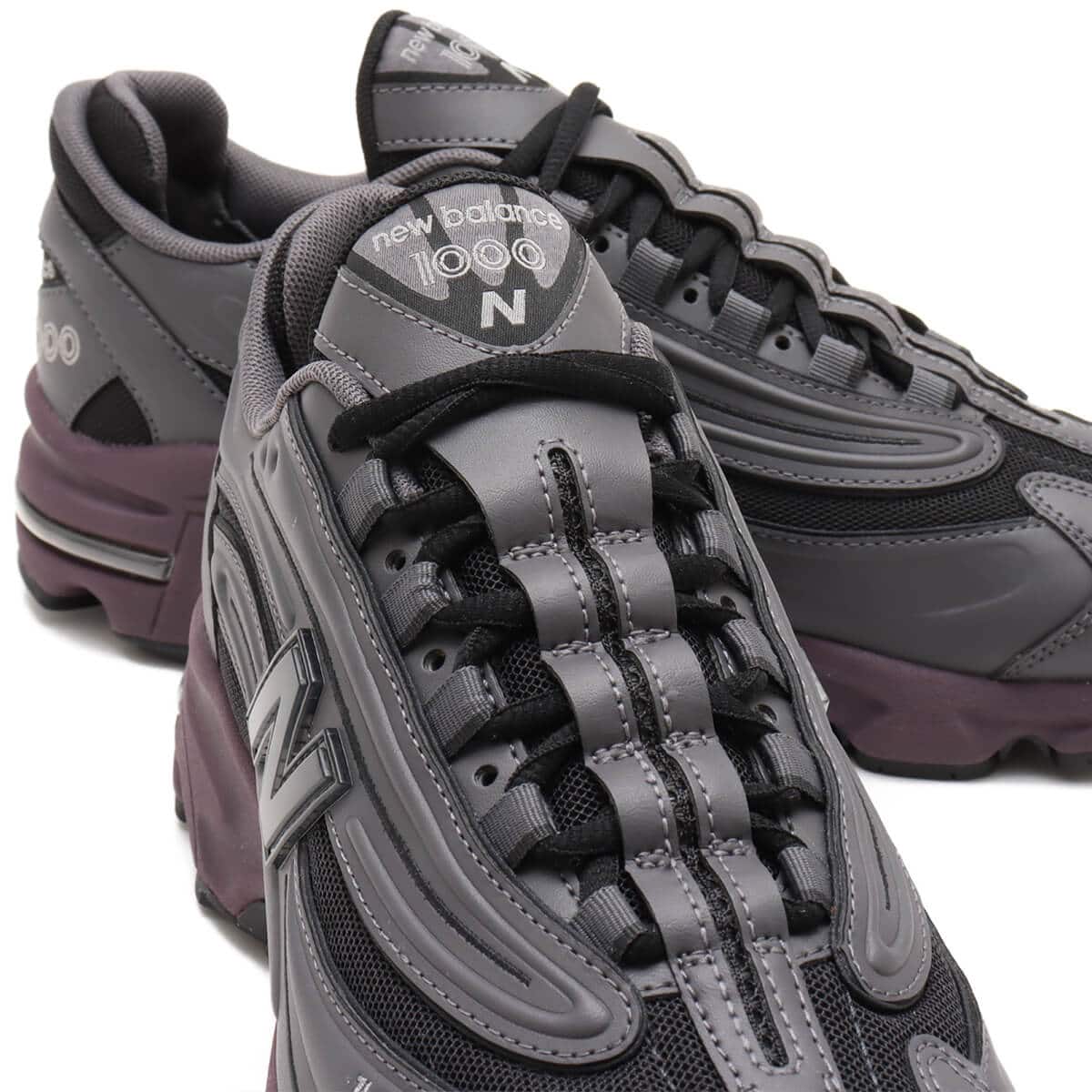 New Balance "Grey Day" inspired grey and black sneaker with plum midsole, leather and mesh construction, and signature "N" logo.