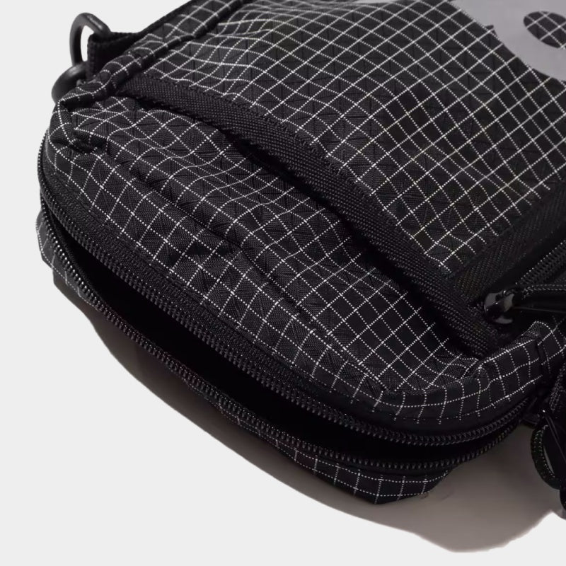 Mini shoulder bag made from durable grid nylon fabric with partition and zipper pockets, featuring a reflective atmos motif for style and nighttime visibility.