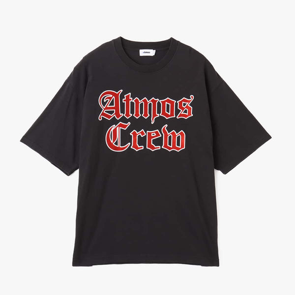 Atmos short-sleeved T-shirt with Old English-style Atmos Crew motif on the front and blue pistag on the left hem, crafted from soft, smooth fabric. Model height 180cm, wearing size L.