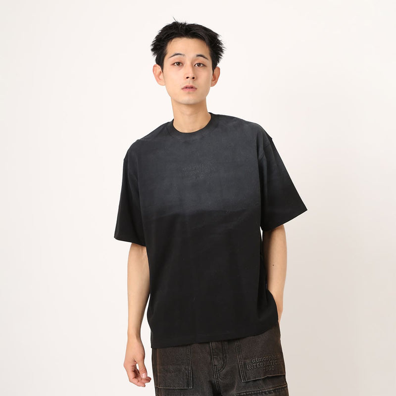 Monochrome T-shirt with tonal front embroidery and gradient rubber spray, worn by model 180cm tall in size L