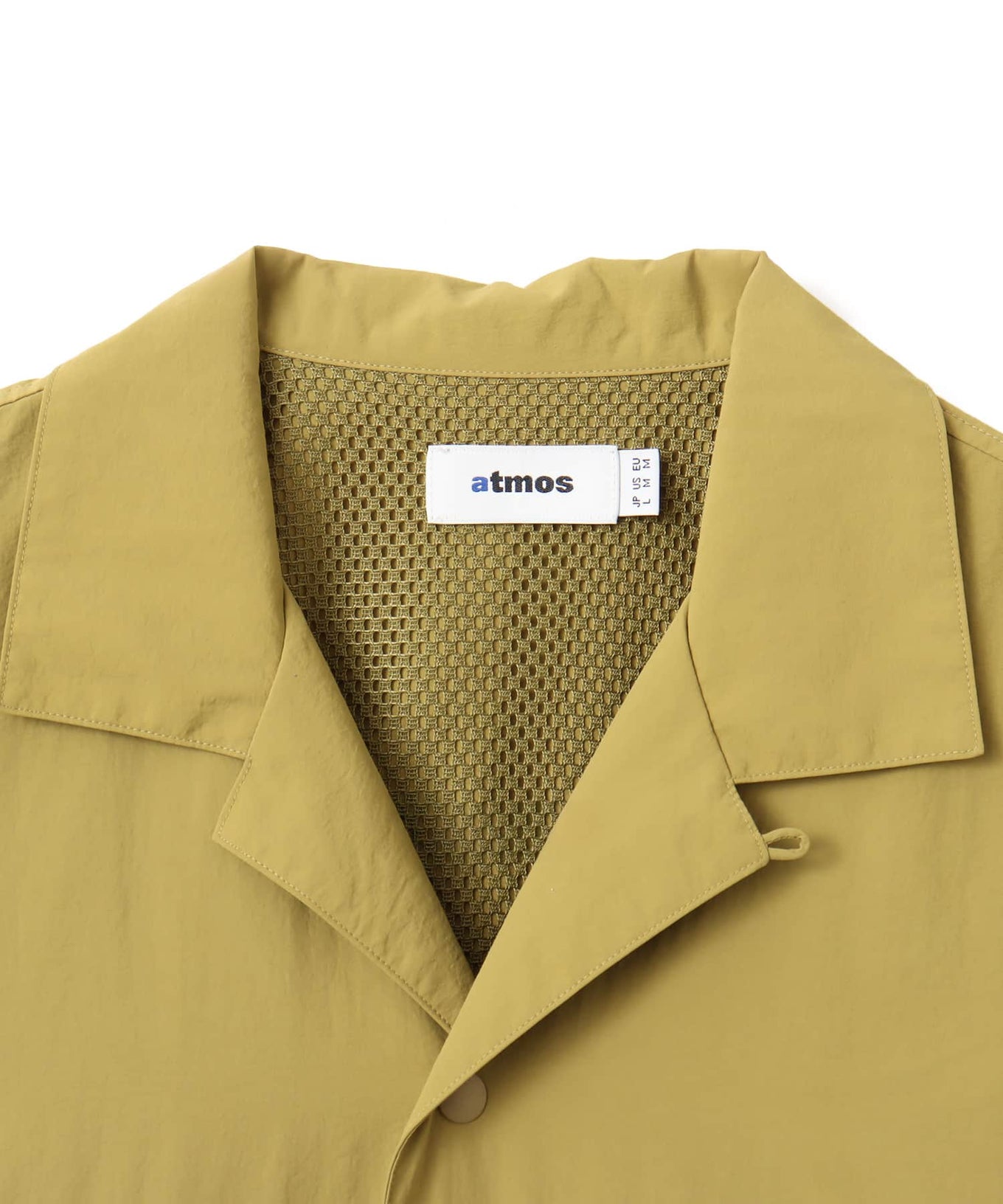 Model wearing a short-sleeved fishing-style nylon shirt with flap pocket and reflective atmos logo.