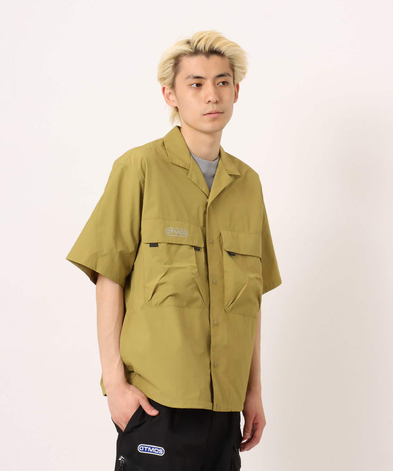 Model wearing a short-sleeved fishing-style nylon shirt with flap pocket and reflective atmos logo.