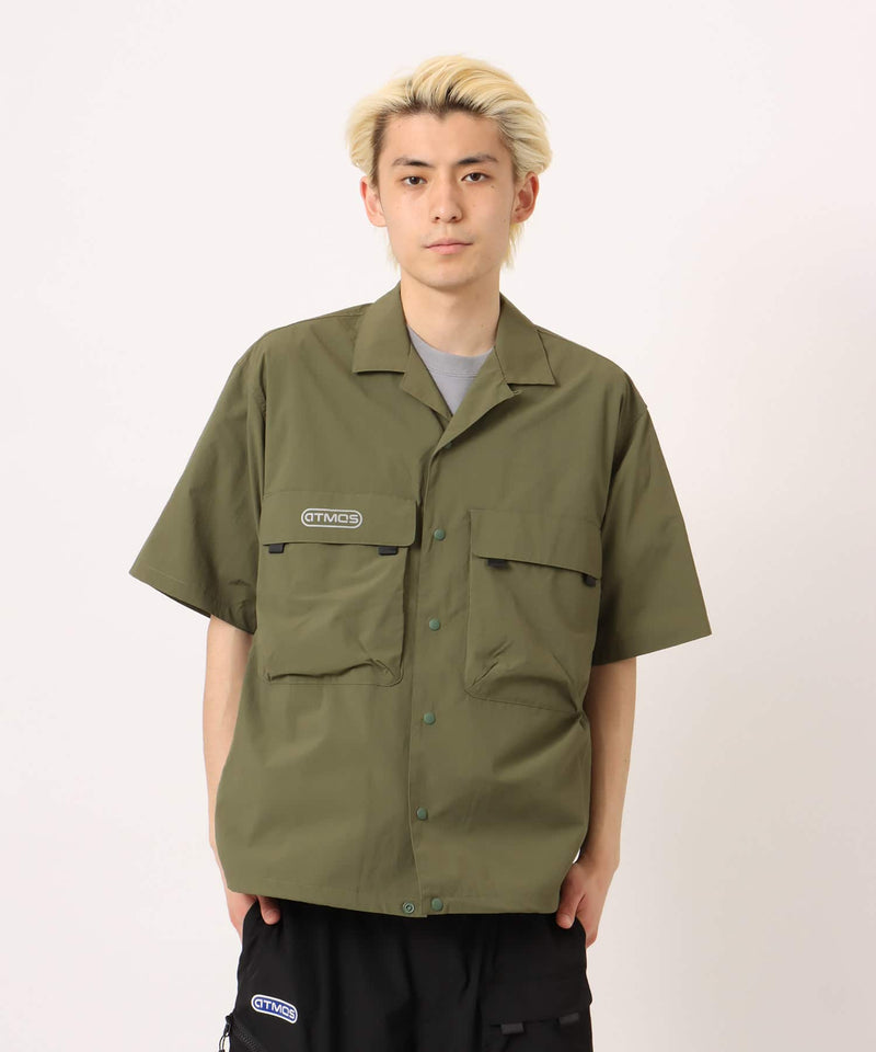 Model wearing a short-sleeved fishing-style nylon shirt with flap pocket and reflective atmos logo.