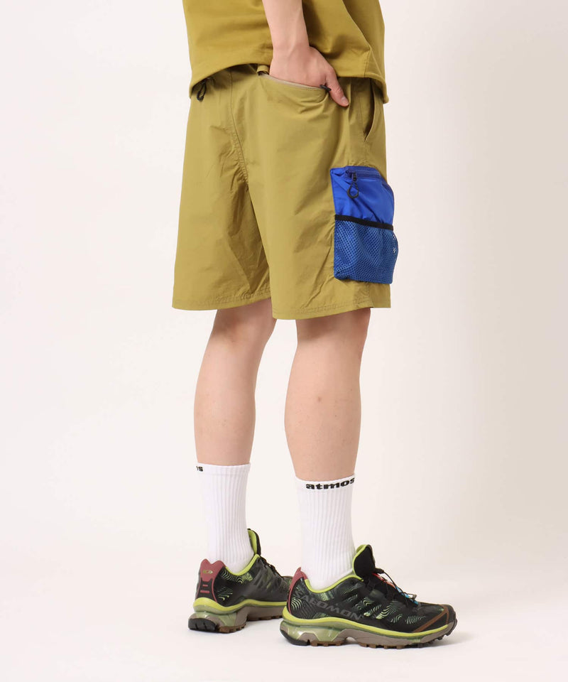Model wearing functional cargo shorts with mesh and flap pockets in durable cotton fabric.