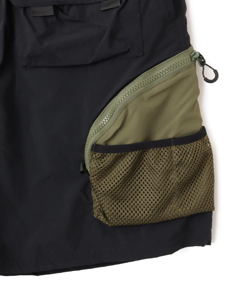 Model wearing functional cargo shorts with mesh and flap pockets in durable cotton fabric.