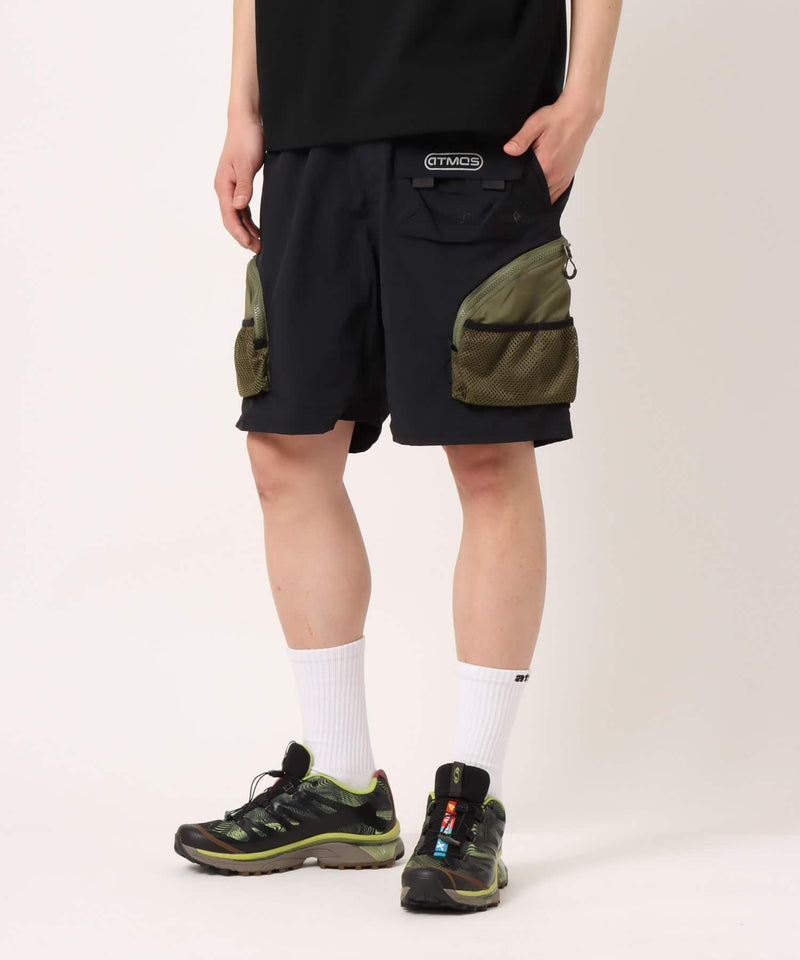 Model wearing functional cargo shorts with mesh and flap pockets in durable cotton fabric.