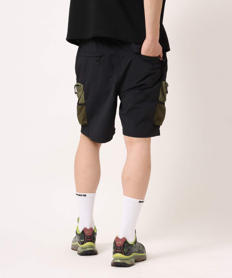 Model wearing functional cargo shorts with mesh and flap pockets in durable cotton fabric.