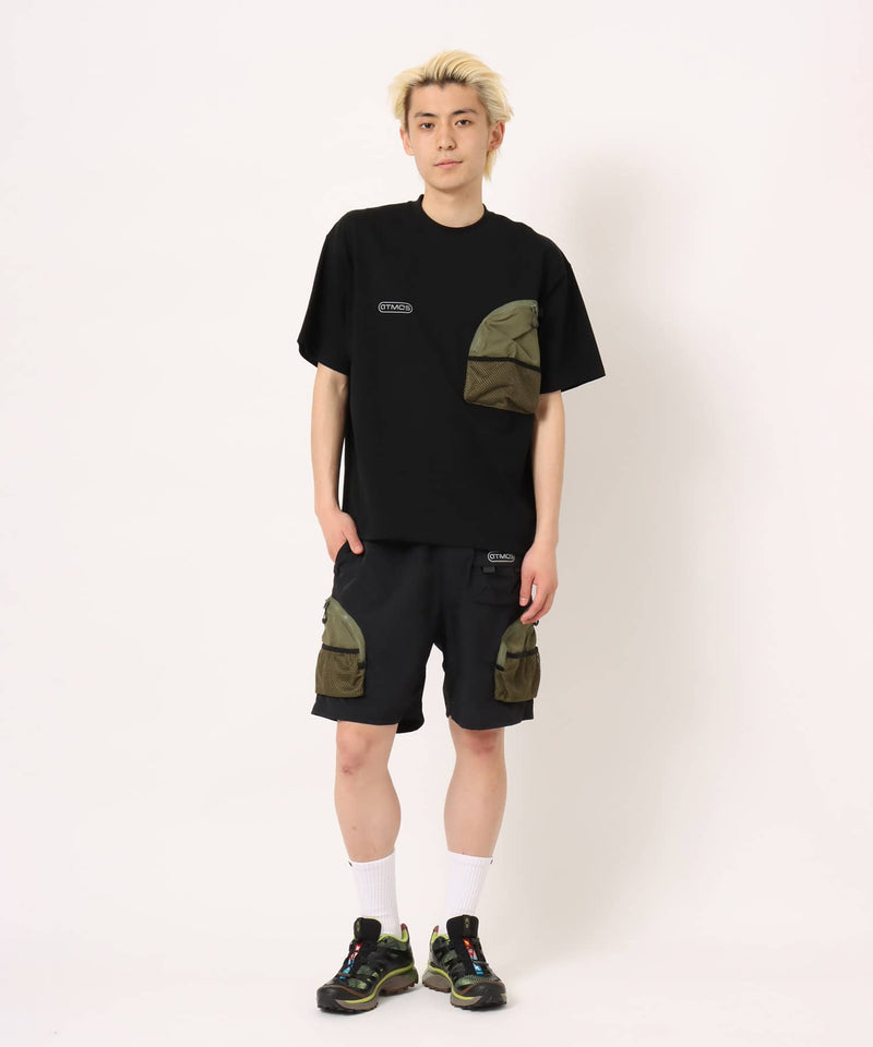 Model wearing functional cargo shorts with mesh and flap pockets in durable cotton fabric.