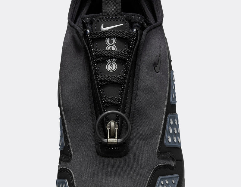 Air Max SNDR sneaker with a bold design featuring Silver accents, a black zip-up shroud, reflective design panels, Max Air cushioning in the heel, and Nike Air in the forefoot. Unzipped shroud reveals ""6453"" representing Nike’s global office numbers.