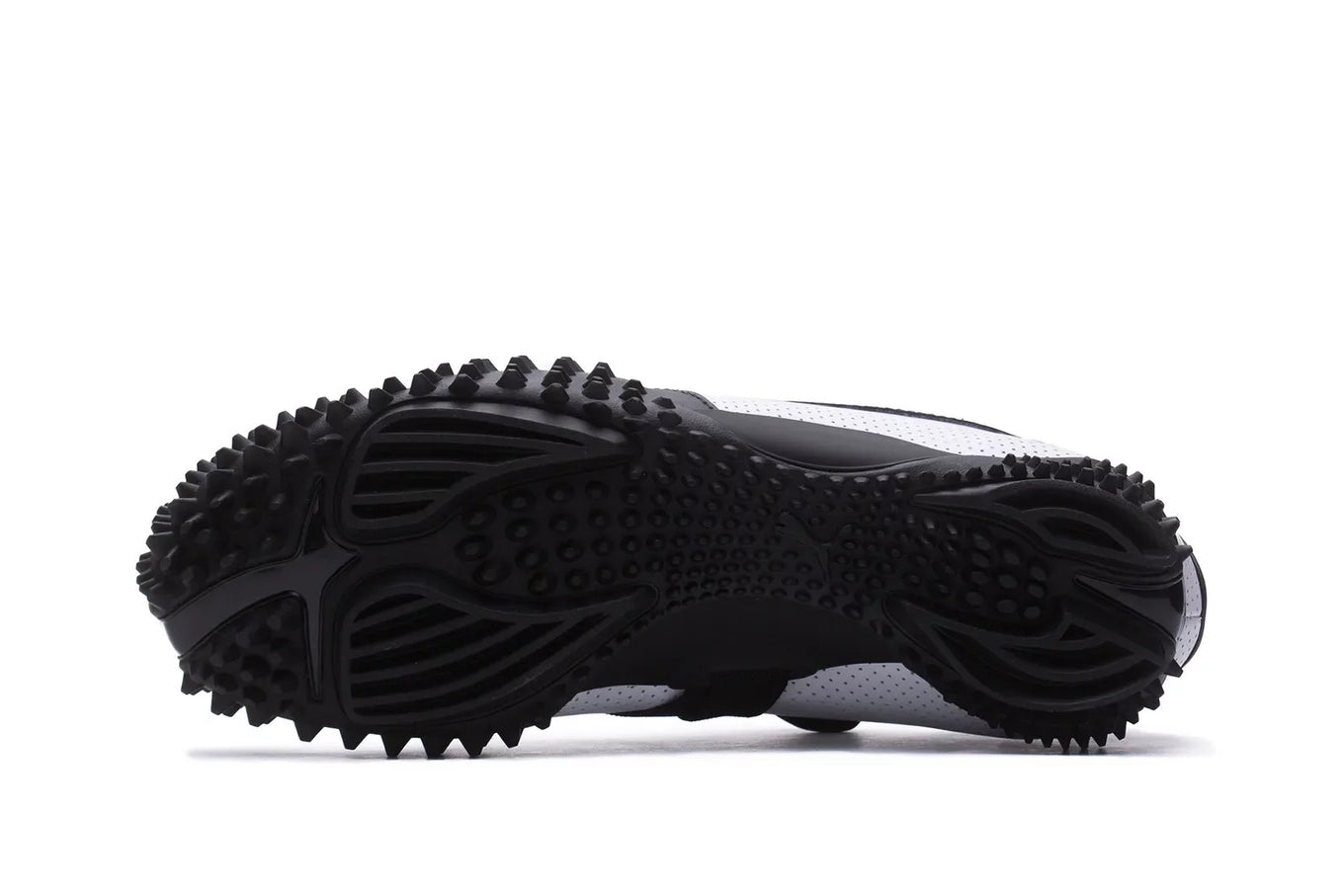 The Puma Mostro features a perforated leather upper, flat silhouette, and iconic Formstrip logo, blending influences from 1960s sprint spikes and 1980s surf shoes.