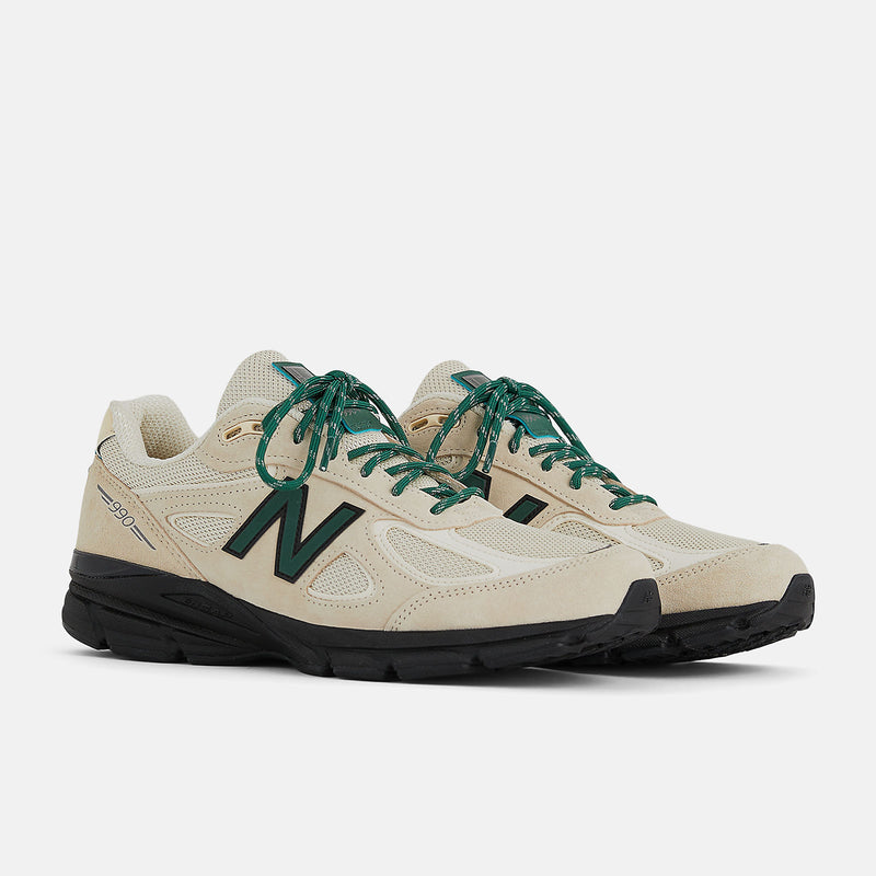 This iconic running shoe showcases the triumphant return of the New Balance 990 v4 after an 8-year hiatus. It features a light beige mesh upper adorned with suede overlays, complemented by black and dark green accents. 