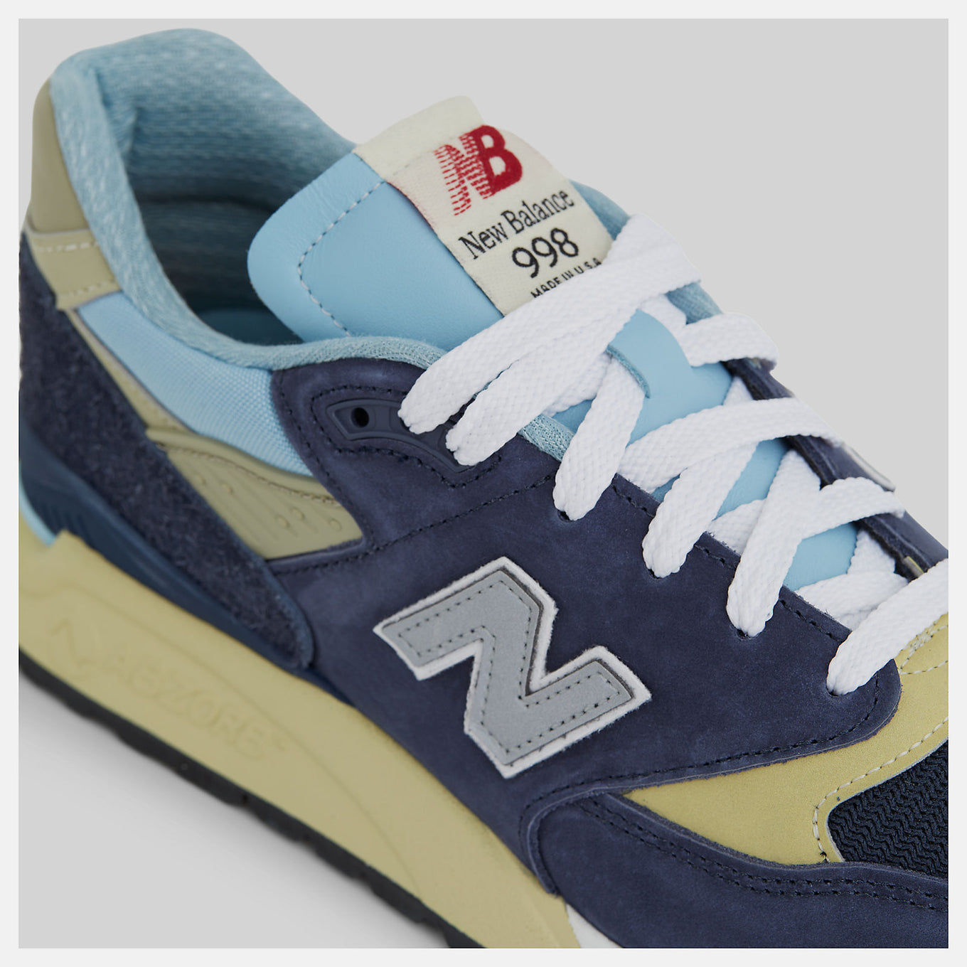 New Balance 998 Made in USA sneakers in navy with chrome blue accents, featuring ABZORB cushioning and premium suede, mesh, and hairy suede construction.