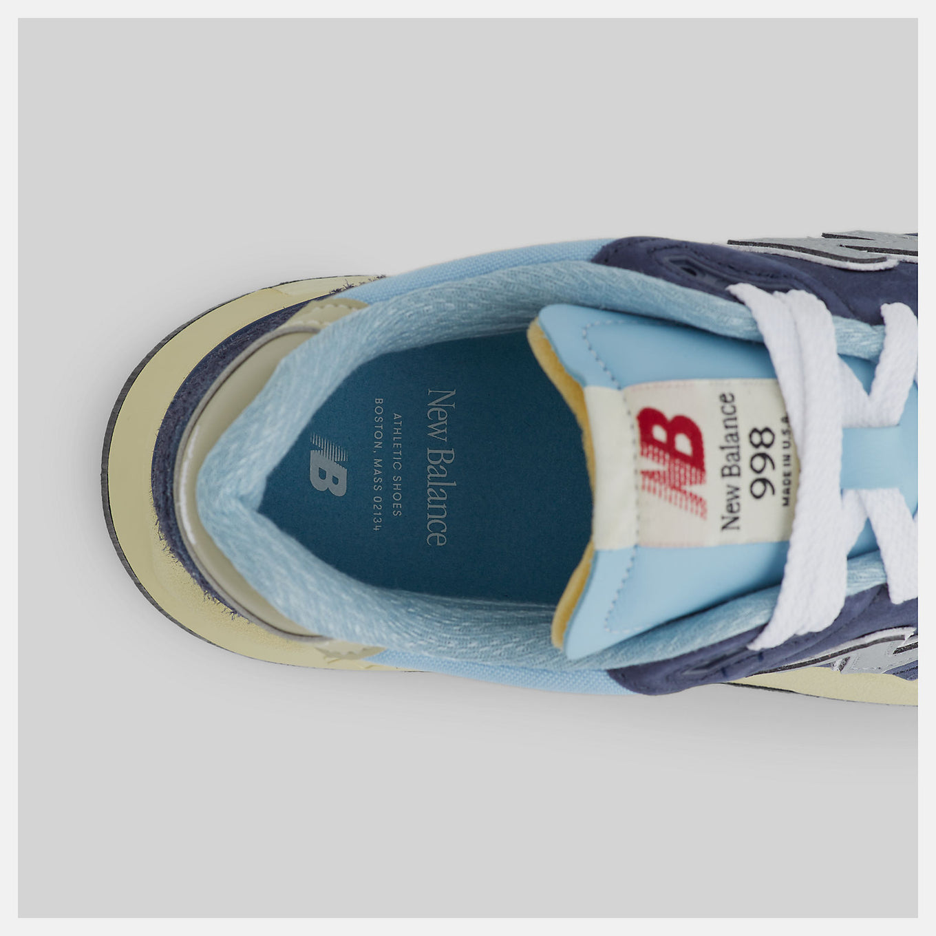 New Balance 998 Made in USA sneakers in navy with chrome blue accents, featuring ABZORB cushioning and premium suede, mesh, and hairy suede construction.