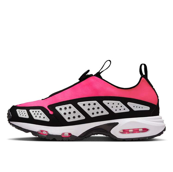 Air Max SNDR sneaker featuring a bold color scheme with black overlays, Hyper Pink shroud, and reflective white panels, equipped with Max Air and Nike Air cushioning. Unzipped shroud reveals "6453," referencing Nike's global office numbers.