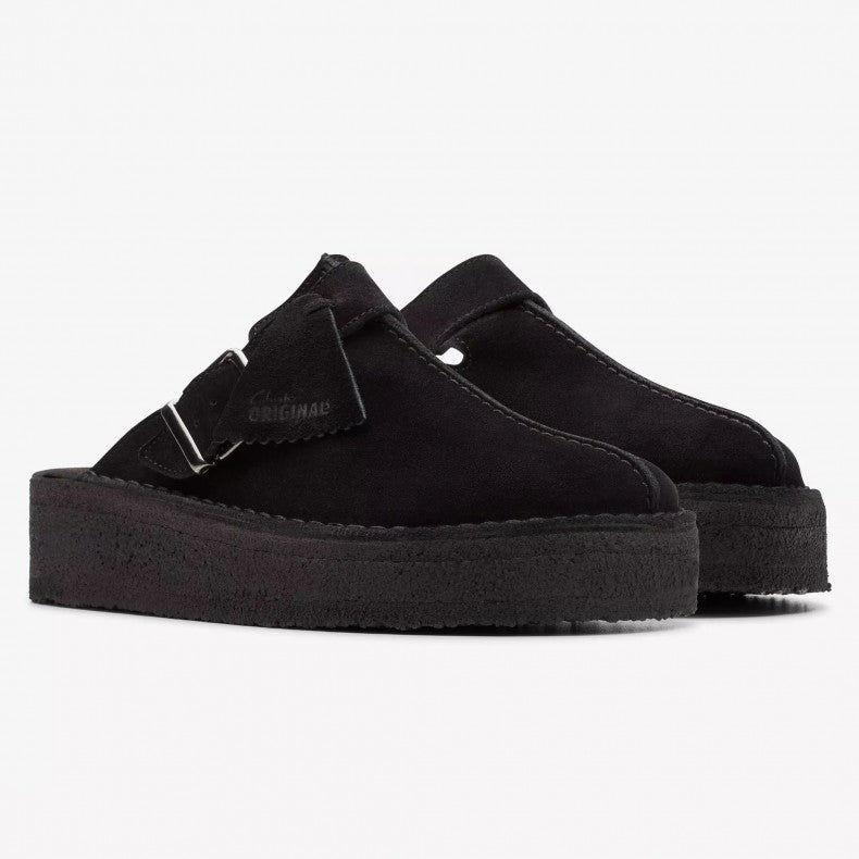 Clarks Originals Trek wedge heel mules in black suede, showcasing a slip-on design with an adjustable pin-buckle strap, center split seam, and rounded toeline