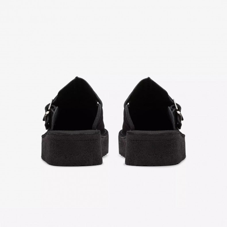 Clarks Originals Trek wedge heel mules in black suede, showcasing a slip-on design with an adjustable pin-buckle strap, center split seam, and rounded toeline