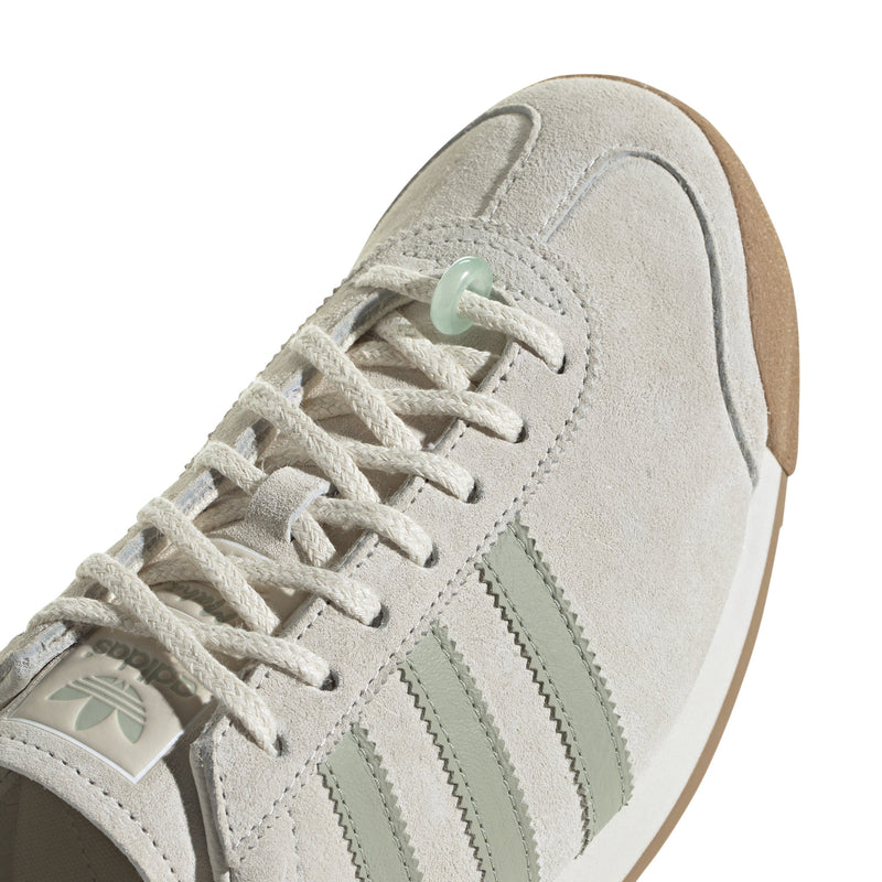 Maha Amsterdam, a prominent women’s streetwear store established in 2015 by Saskia van Hofwegen and Dian Iskandar, collaborates with adidas on the classic sneaker from the late '70s—the adidas Samoa. This design features a low-cut silhouette with a suede upper in "Chalk White," complemented by subtle green accents, comfortable padding, and a cushioned sole. The laces include a jade-colored lace jewel, along with adidas and Maha logo details for added flair.